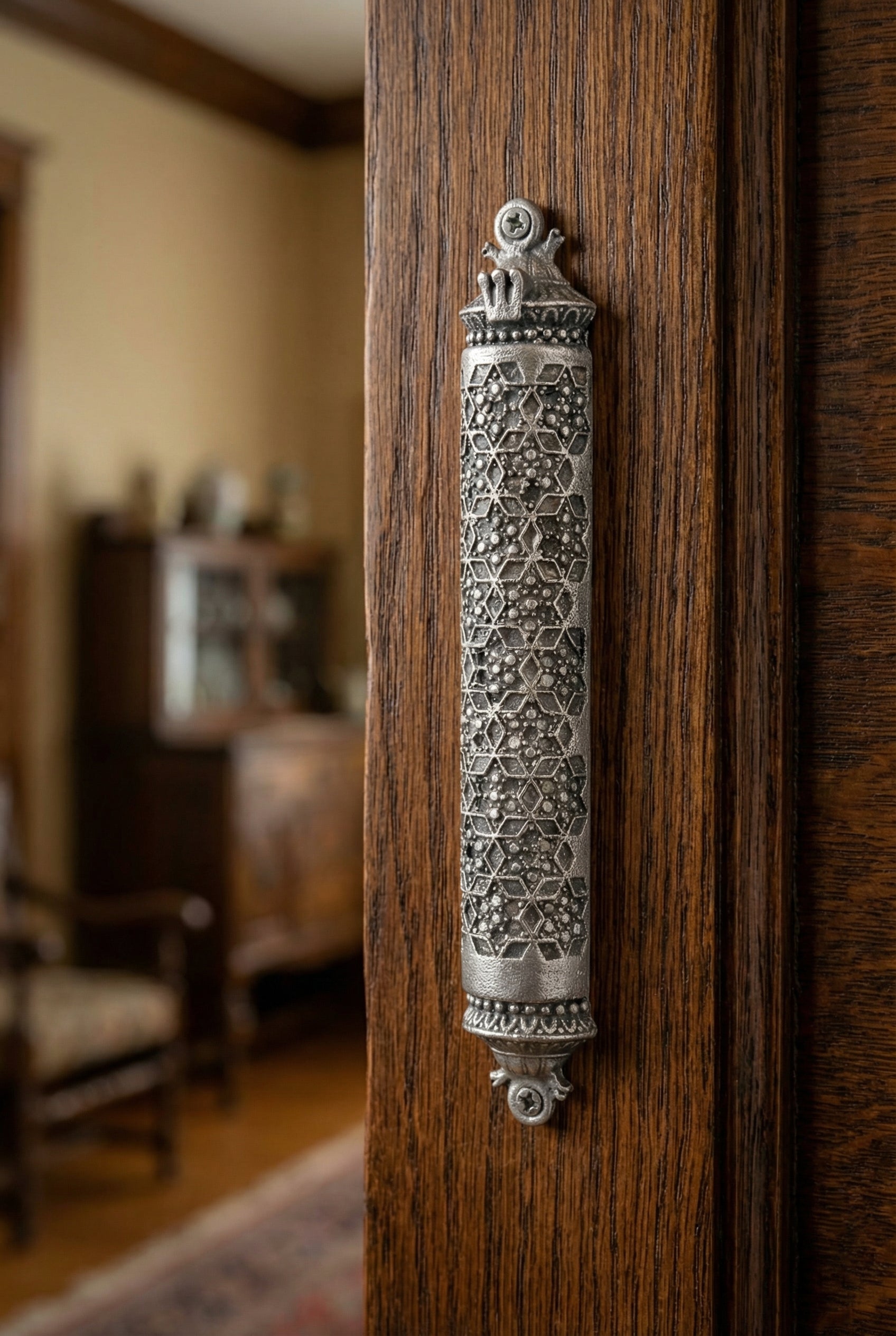 Traditional Mosaic Magen David Pewter Mezuzah mounted vertically on a richly textured wooden door
