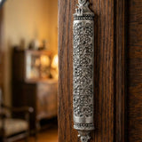 Traditional Mosaic Magen David Pewter Mezuzah, mounted vertically on a rustic wooden door in a warmly lit traditional Jewish home