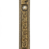 A detailed high-resolution image of an Ariel Brass Mezuzah with engraved Hebrew letters and decorative motifs, set against a pure white background with a soft reflection.