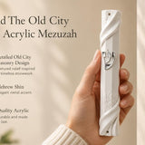 Person holding an opaque white acrylic mezuzah with Jerusalem-inspired wall relief and a silver Shin.