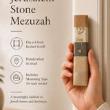 Close-up of a hand holding an authentic Jerusalem stone mezuzah case, showcasing its unique mineral tones and Hebrew design.