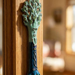 Close-up of Avatar Mezuzah on wooden door frame highlighting pewter texture and hand-painted enamel details in blue and green.