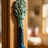Close-up of Avatar Mezuzah on wooden door frame highlighting pewter texture and hand-painted enamel details in blue and green.