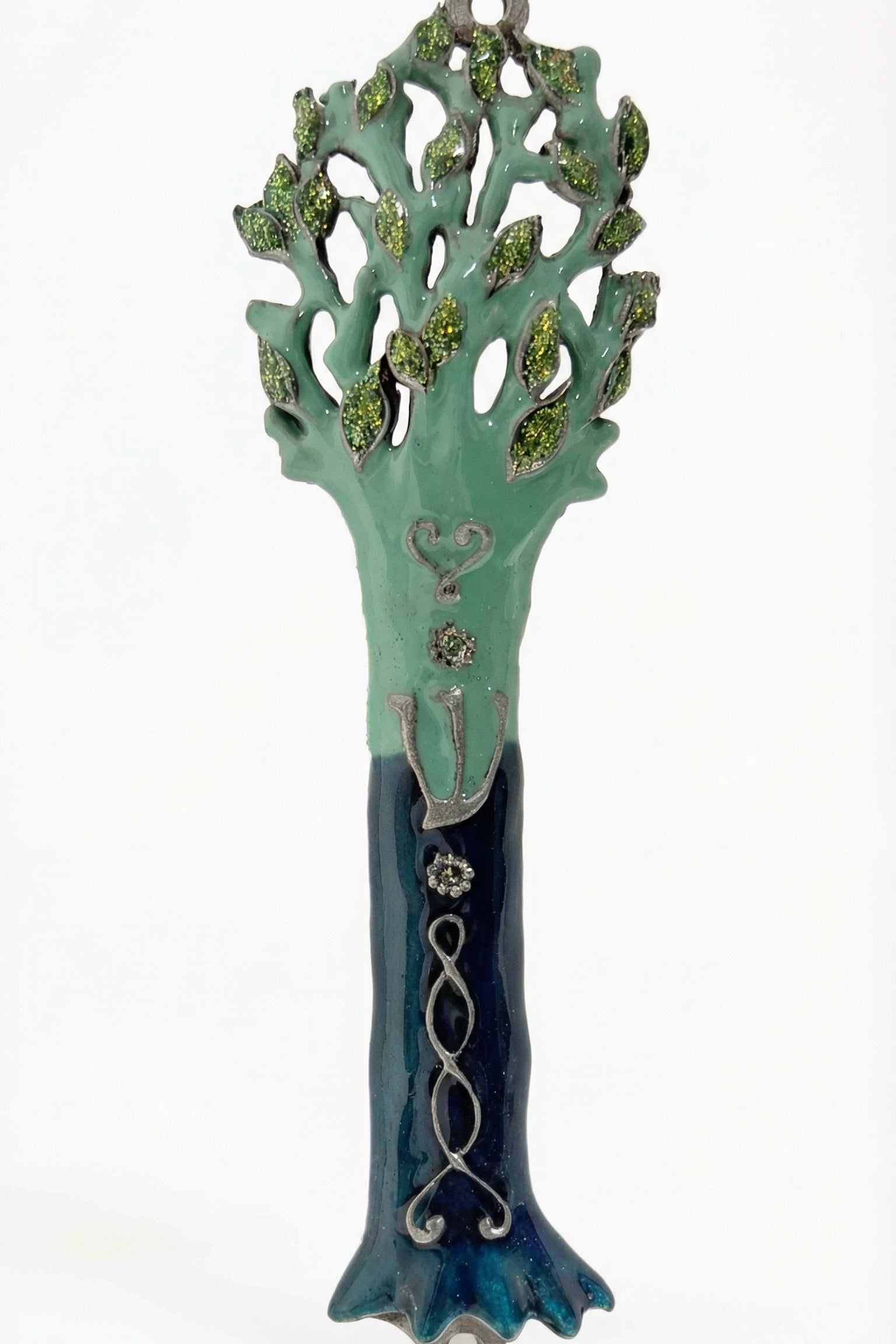 Detailed photo of an Avatar Mezuzah made of pewter, hand-painted with enamel, displayed on a clean white studio background with soft reflection.