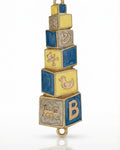 Hand painted blue and yellow baby mezuzah made of brass with enamel paint, 4 inches tall, displayed on a white background with soft reflection.