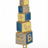 Hand painted blue and yellow baby mezuzah made of brass with enamel paint, 4 inches tall, displayed on a white background with soft reflection.