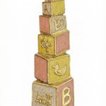 Hand-painted brass baby mezuzah in pink and yellow, 4 inches tall with Hebrew inscription, designed for nursery decor, with a bright white background.
