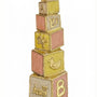 Hand-painted brass baby mezuzah in pink and yellow, 4 inches tall with Hebrew inscription, designed for nursery decor, with a bright white background.