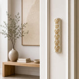 Baroque style gold and Jerusalem stone mezuzah case mounted vertically on a residential doorpost.
