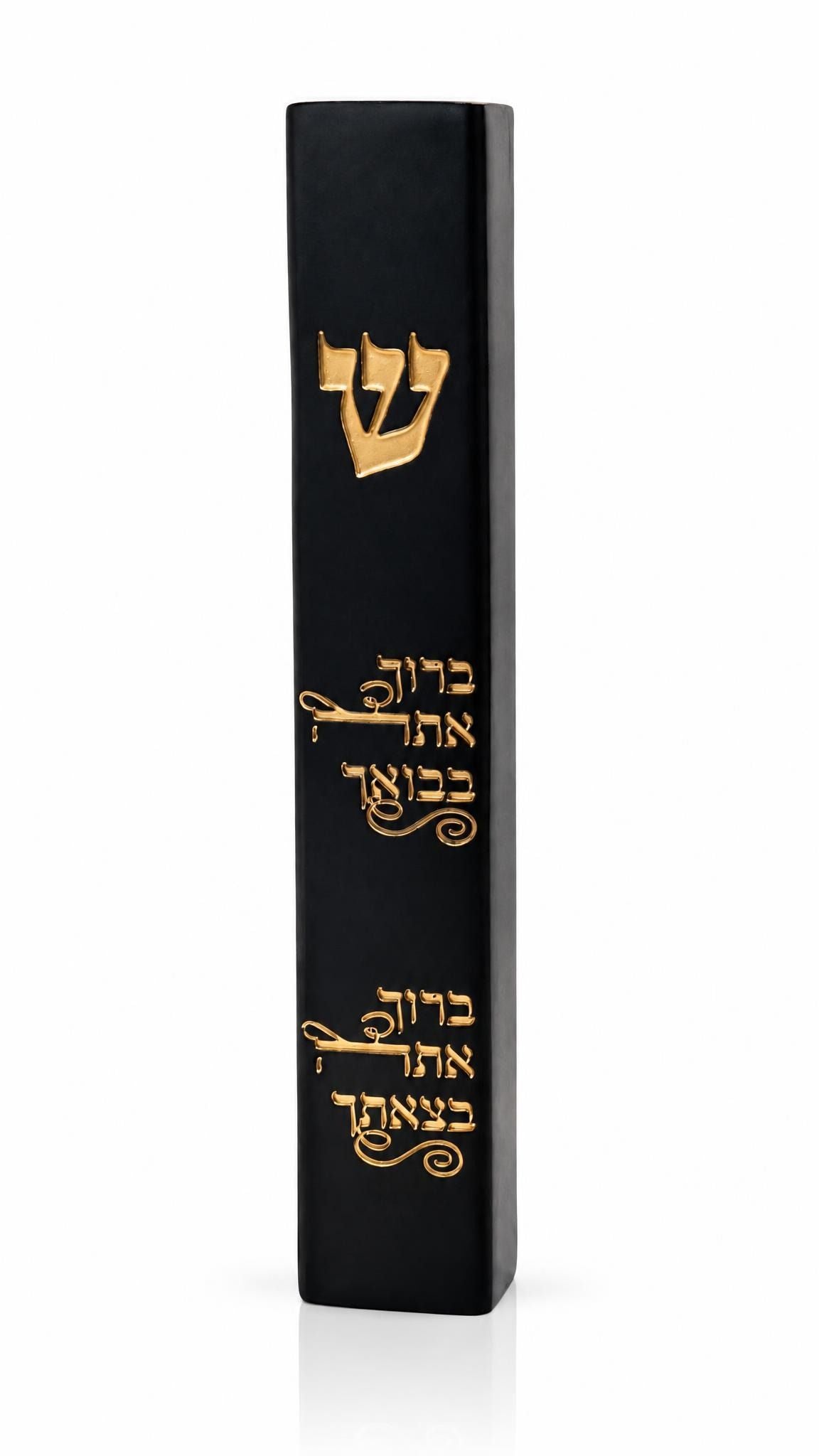 the Baruch Atah Blessed Black Concrete Mezuzah case on a white background, showing its smooth black face, engraved gold Shin, and two engraved Hebrew lines blessing arrival and departure