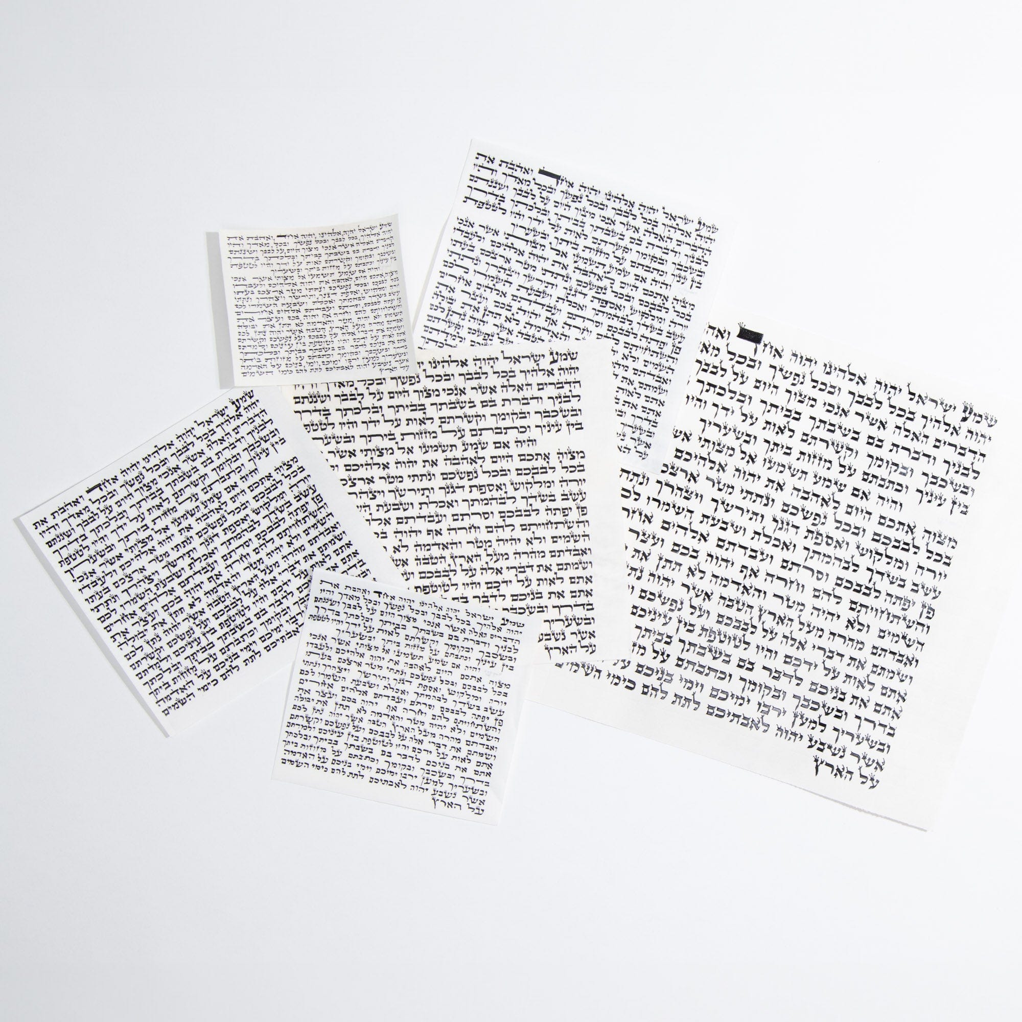 Basic 100% kosher mezuzah scrolls shown laid flat with handwritten Hebrew text on genuine mezuzah parchment