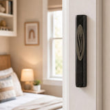 Black marble mezuzah case mounted on a residential doorpost in an indoor setting, highlighting natural stone patterns and craftsmanship.