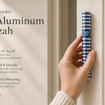 Person holding a blue aluminum mezuzah with silver Shin and grooved round design, in a premium editorial style for a store feature.
