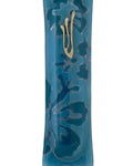 Blue glass mezuzah with detailed Hebrew inscriptions, engraved motifs, and textured surface, displayed on a clean white background with subtle reflection.