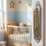 Lifestyle image of a pewter and brass giraffe mezuzah with blue jewel accents on inside wall of doorway, in a home setting.