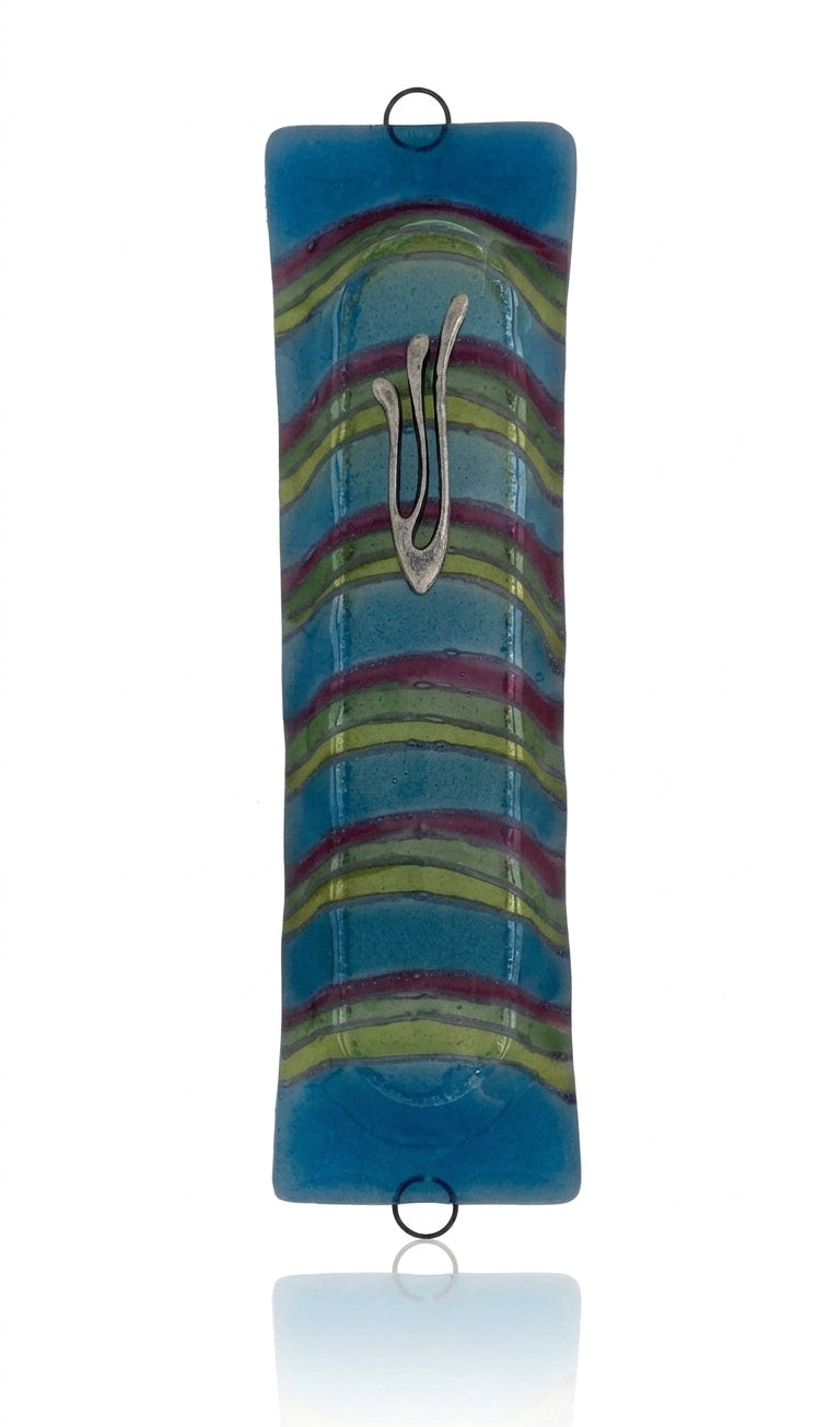 Blue Lagoon glass mezuzah with Hebrew symbols, detailed carvings, and decorative motifs on a polished white background with soft reflection.