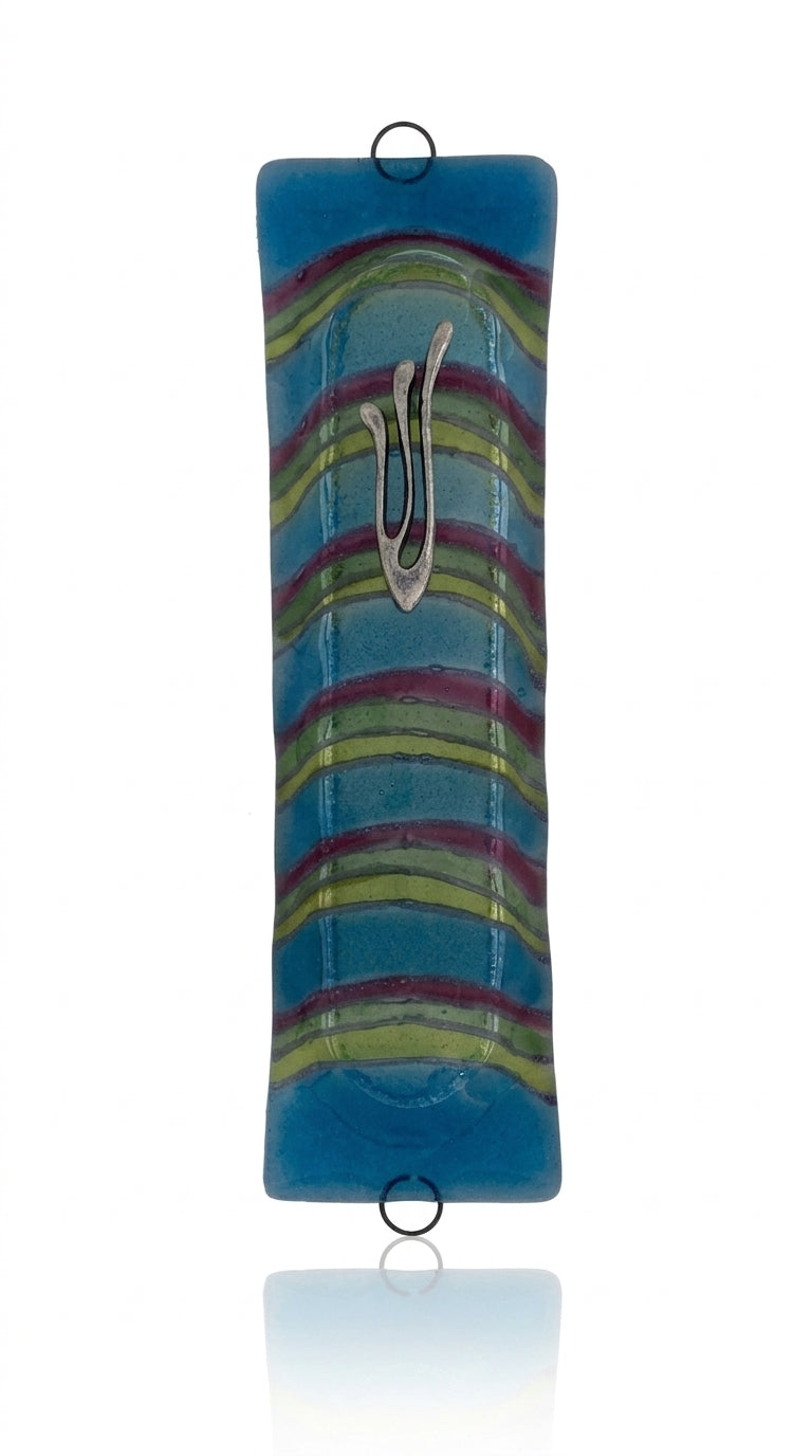 Blue Lagoon glass mezuzah with Hebrew symbols, detailed carvings, and decorative motifs on a polished white background with soft reflection.