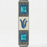 Petite blue stone mezuzah with Hebrew Shin letter and sparkling accents, made of pewter, designed for home doorposts with a polished white background.