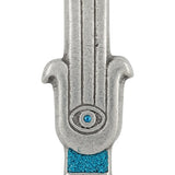 Blue Hamsa shaped Mezuzah with a central eye symbol, accented with silver and blue sparkling paint, placed on a white studio surface with soft reflection.
