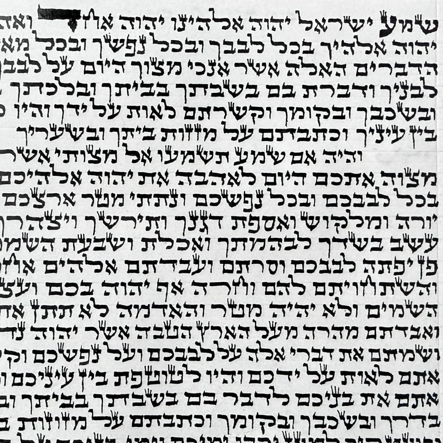 a certified kosher mezuzah klaf handwritten on parchment by a sofer STaM, showing the Hebrew Shema passages in traditional sacred scribal lettering