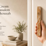 Person naturally holding the Classic cream Jerusalem stone mezuzah case, emphasizing its authentic vein textures and Hebrew shin details