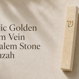 Cream Jerusalem stone mezuzah case with gold-tone Shin mounted on a pale limestone surface