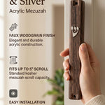 Person holding a classic brown woodgrain acrylic mezuzah with a silver Shin letter in a brightly lit editorial setting.