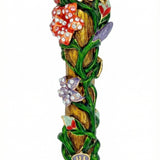 Vibrant brass mezuzah decorated with colorful flowers, intertwined vines, accent stones, layered details, and Hopeful rays on a pure white background with a subtle reflection.