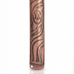 High-resolution image of a petite copper mezuzah with intricate design, Hebrew engravings, and a bright copper finish, on a white studio surface.