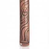 High-resolution image of a petite copper mezuzah with intricate design, Hebrew engravings, and a bright copper finish, on a white studio surface.