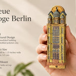 Die Neue Synagoge Berlin Mezuzah mezuzah cover held upright in one hand, showing golden ochre Fimo polymer clay shaped as the Berlin synagogue facade, with gray domes, tall windows and fine architectural relief beside the product name and illustrated design features in a wide social-sharing graphic for decorative Jewish home Judaica