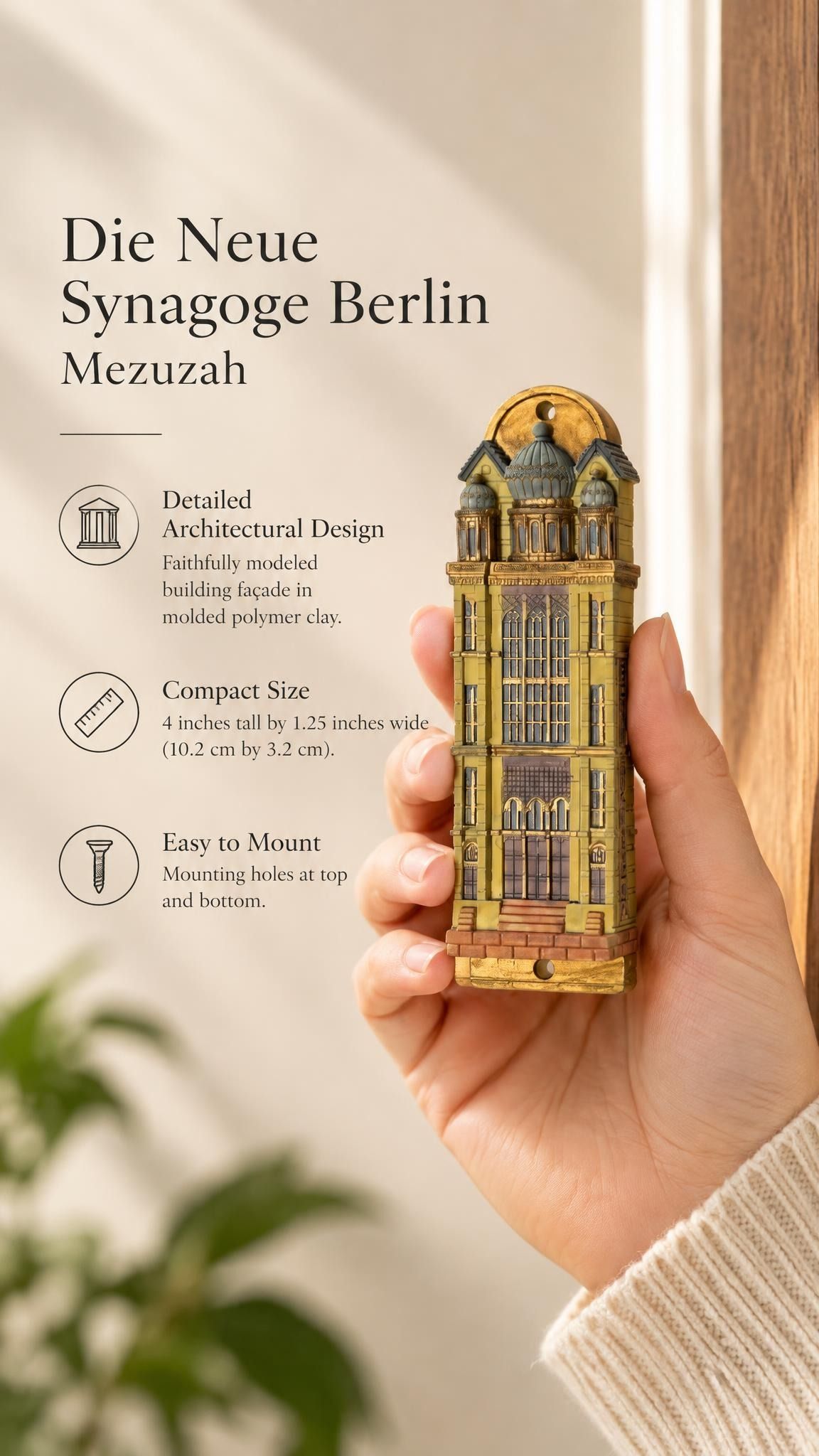 Handheld portrait of the Die Neue Synagoge Berlin Mezuzah mezuzah cover, with golden ochre Fimo polymer clay shaped as the Berlin synagogue facade, with gray domes, tall windows and architectural relief clearly visible beside the product name and illustrated features of this distinctive Jewish doorway design
