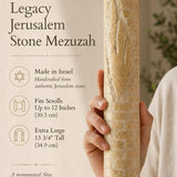 Hand holding the carved Jerusalem Stone Mezuzah against a neutral background, emphasizing its architectural texture and monumental Shin design.