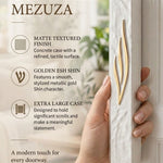 Extra large white concrete mezuzah with a golden Shin held in hand against a neutral editorial background.