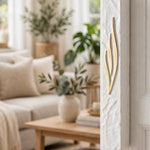 Extra Large Golden Esh White Concrete Mezuzah mounted on a white doorpost beside a sunlit living room, its hand-textured white surface and tall flame-shaped gold Shin showing the scale of this waterproof 8-inch scroll mezuzah case