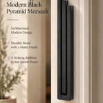 Extra Large Modern Black Pyramid Mezuzah mounted on a pale doorpost beside its product name and illustrated design features, showing the deep matte black aluminum mezuzah cover and three stepped bars as a minimalist detail for a Jewish home entrance