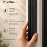 Extra Large Modern Black Pyramid Mezuzah held beside a doorpost, with the deep matte black aluminum mezuzah cover shown close enough to reveal its three stepped bars and rounded lower edge alongside product-name and design callouts for this minimalist Judaica piece