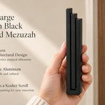 Extra Large Modern Black Pyramid Mezuzah pictured in hand as a deep matte black aluminum mezuzah cover with three graduated bars and a minimalist stepped design, alongside its name and illustrated product features in a wide social-sharing image
