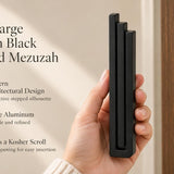 Extra Large Modern Black Pyramid Mezuzah pictured in hand as a deep matte black aluminum mezuzah cover with three graduated bars and a minimalist stepped design, alongside its name and illustrated product features in a wide social-sharing image