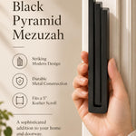 Hand holding the Extra Large Modern Black Pyramid Mezuzah upright, revealing its deep matte black aluminum mezuzah cover, slender three-bar Pyramid design and graduated top beside illustrated product features for minimalist Jewish home Judaica