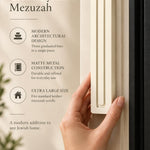 Extra Large Modern Cream Pyramid Mezuzah held beside a doorpost, with the warm ivory cream aluminum mezuzah cover shown close enough to reveal its three stepped bars and rounded lower edge alongside product-name and design callouts for this architectural Judaica piece