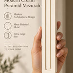 A hand presents the Extra Large Modern Cream Pyramid Mezuzah with its warm ivory cream aluminum mezuzah cover facing forward, highlighting the clean graduated bars and geometric vertical profile beside design illustrations for a architectural Jewish doorway accent