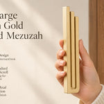 Extra Large Modern Gold Pyramid Mezuzah pictured in hand as a warm metallic gold aluminum mezuzah cover with three graduated bars and a minimalist stepped design, alongside its name and illustrated product features in a wide social-sharing image