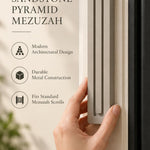 Extra Large Modern Sandstone Pyramid Mezuzah held beside a doorpost, with the warm taupe sandstone aluminum mezuzah cover shown close enough to reveal its three stepped bars and rounded lower edge alongside product-name and design callouts for this minimalist Judaica piece