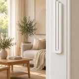 Extra Large Modern White Pyramid Mezuzah mounted vertically on a white interior doorpost, where its smooth matte white aluminum mezuzah cover and three graduated bars create a contemporary Judaica accent with clean geometric lines against the pale doorframe