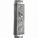 Handcrafted sterling silver mezuzah with intricate filigree and engraved Hebrew symbols, on a pure white background with soft reflection.
