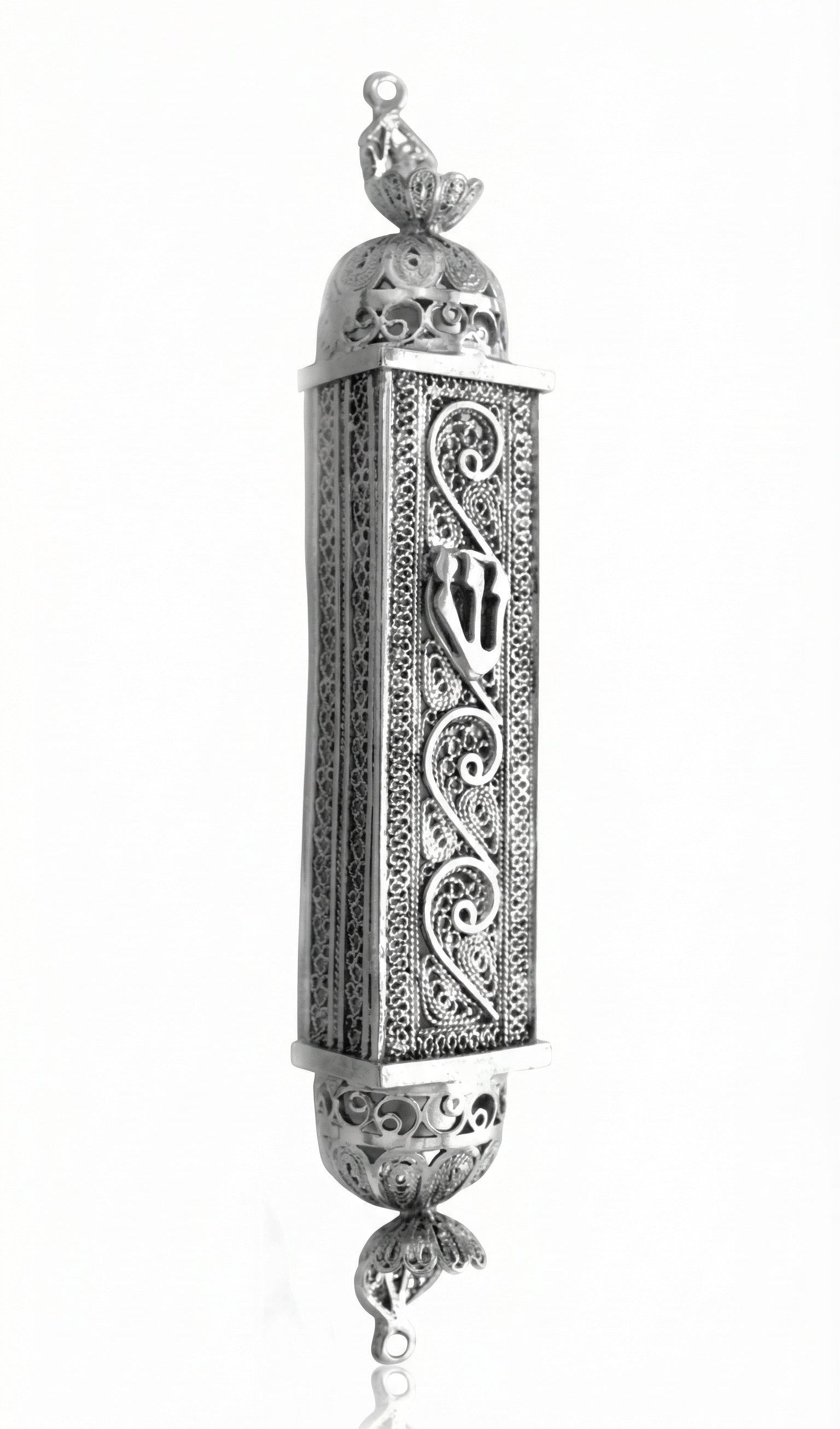 Handcrafted sterling silver mezuzah with intricate filigree and engraved Hebrew symbols, on a pure white background with soft reflection.