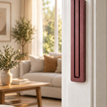 Giant Modern Burgundy Pyramid Mezuzah mounted vertically on a white interior doorpost, where its muted burgundy wine-red aluminum mezuzah cover and three graduated bars create a architectural Judaica accent with clean geometric lines against the pale doorframe