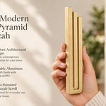 Giant Modern Gold Pyramid Mezuzah pictured in hand as a warm metallic gold aluminum mezuzah cover with three graduated bars and a architectural stepped design, alongside its name and illustrated product features in a wide social-sharing image