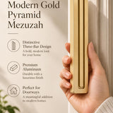 A hand presents the Giant Modern Gold Pyramid Mezuzah with its warm metallic gold aluminum mezuzah cover facing forward, highlighting the clean graduated bars and geometric vertical profile beside design illustrations for a architectural Jewish doorway accent